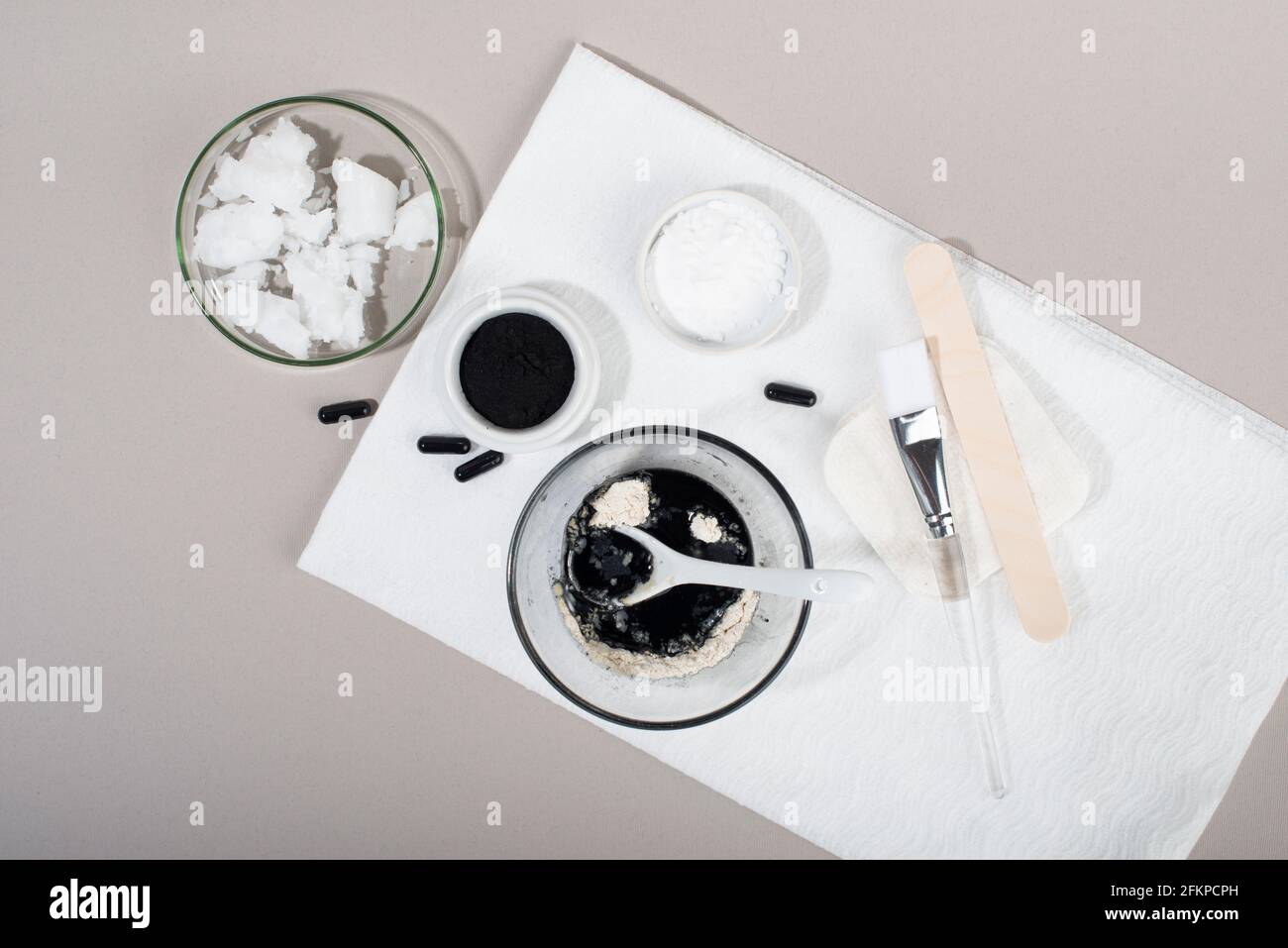 Ingrédients pour un masque facial au charbon de bois maison. Poudre de charbon de bois, huile de coco, argile cosmétique blanche. Concept beauté maison. Flat lay, vue de dessus. Banque D'Images