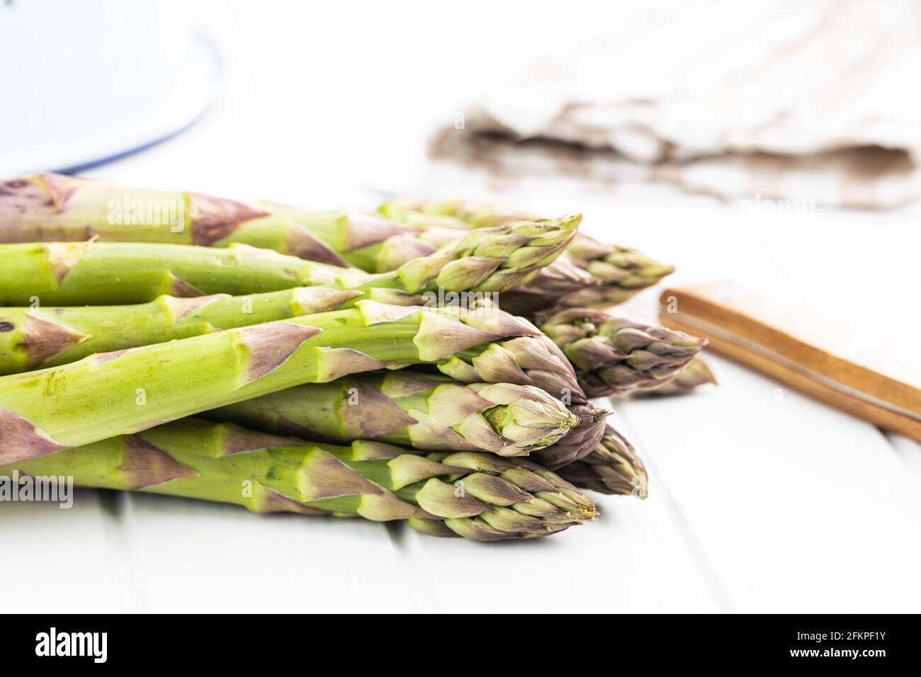 Asperges vertes non cuites fraîches sur table blanche. Banque D'Images