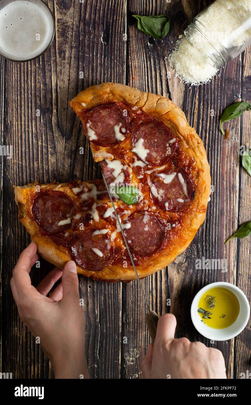 Pizza au pepperoni sur fond de bois. Pizza coupée en tranches et cheesy ...