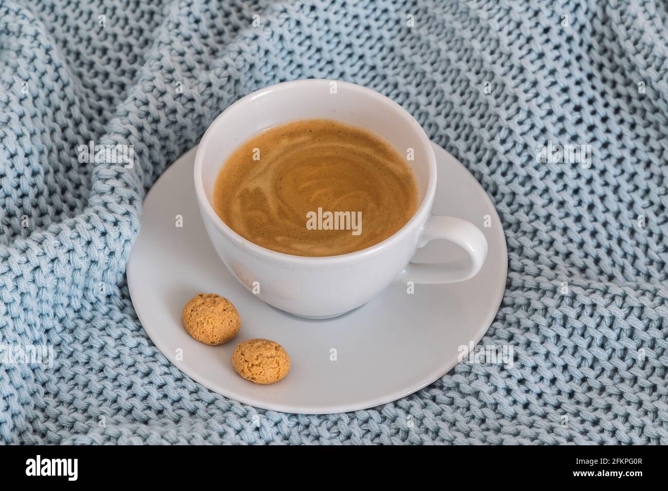 Tasse de café sur une couverture en laine tricotée bleu clair. Atmosphère chaleureuse. Pause-café, concept séjour à la maison. Banque D'Images