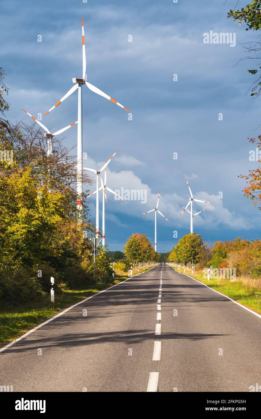 Éoliennes le long d'une rue par temps venteux avec ciel nuageux. Production d'énergie alternative. Photo de stock verticale avec espace de copie. Banque D'Images