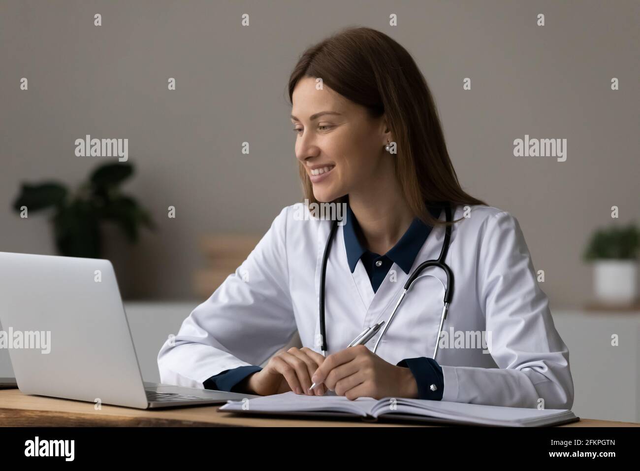 Femme souriante médecin travaille sur un ordinateur portable en ligne Banque D'Images