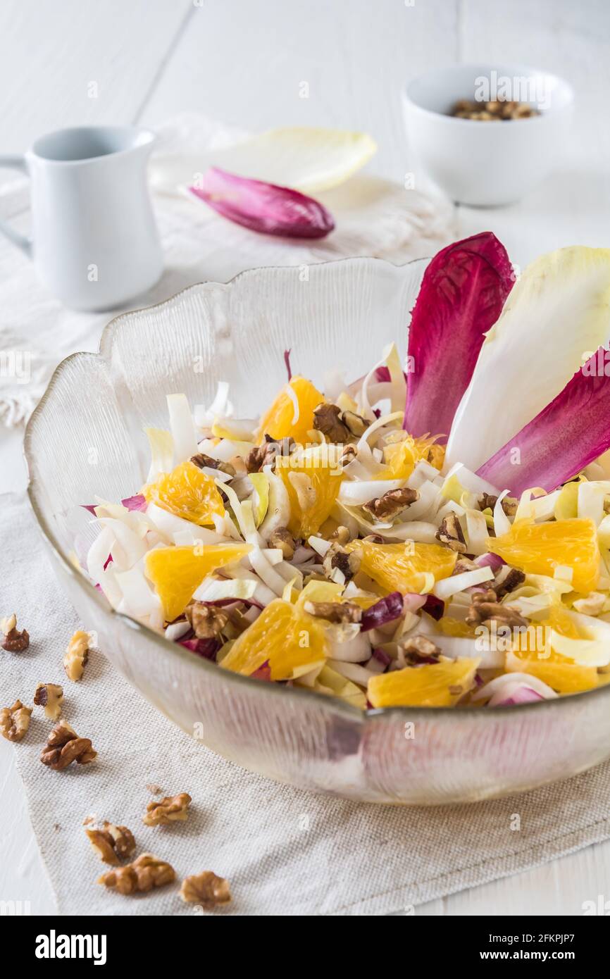 Salade de chicorée à l'orange et aux noix sur fond blanc, verticale Banque D'Images