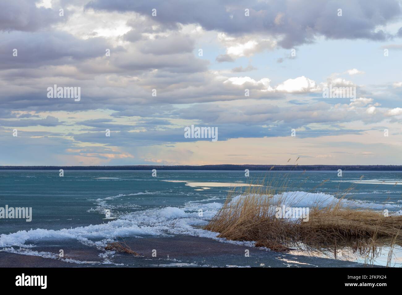 plage côtière et eau avec fonte de glace lac au printemps avec de beaux nuages dans le ciel pendant le coucher du soleil Banque D'Images