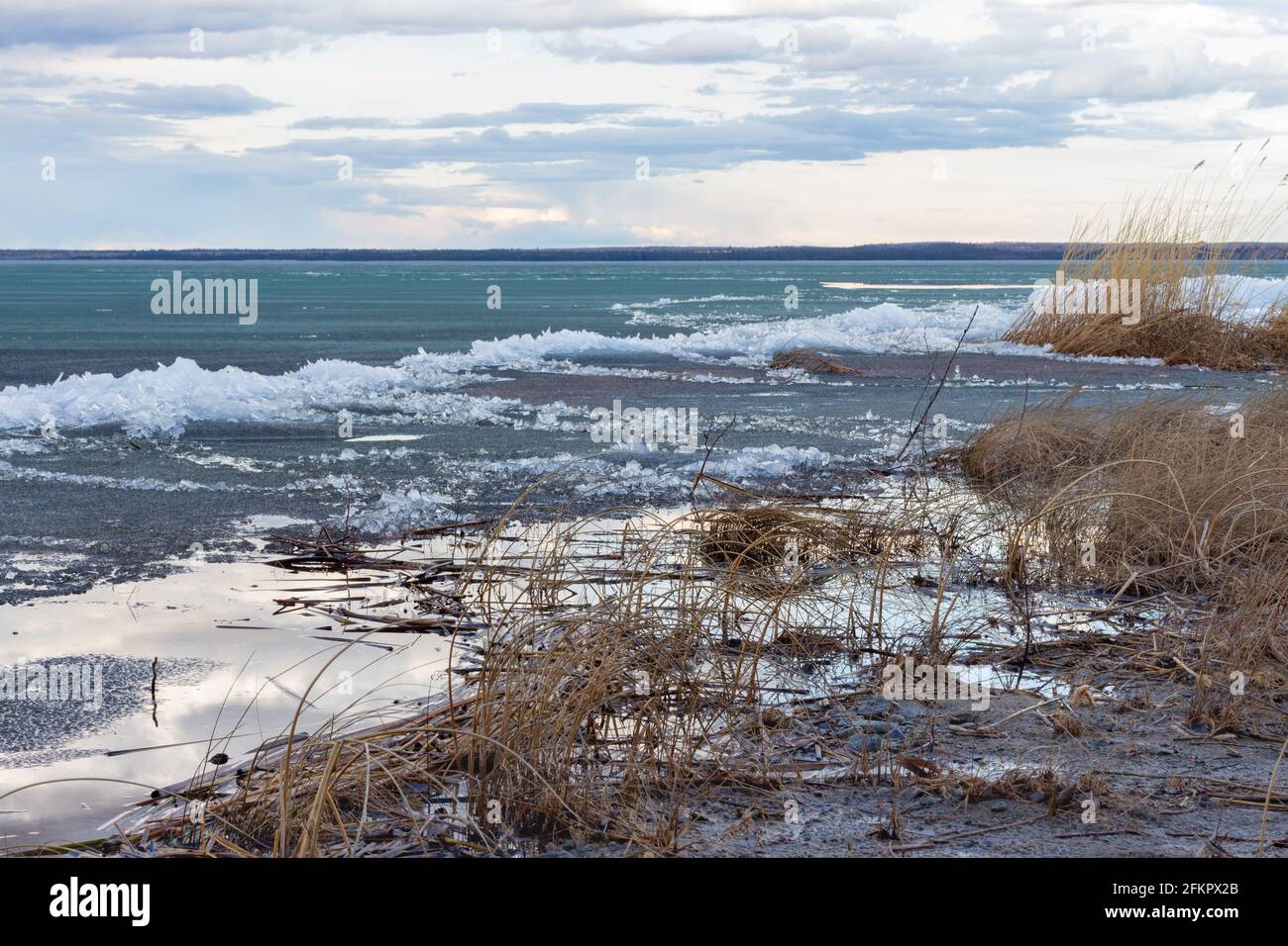 plage côtière et eau avec fonte de glace lac au printemps avec de beaux nuages dans le ciel pendant le coucher du soleil Banque D'Images