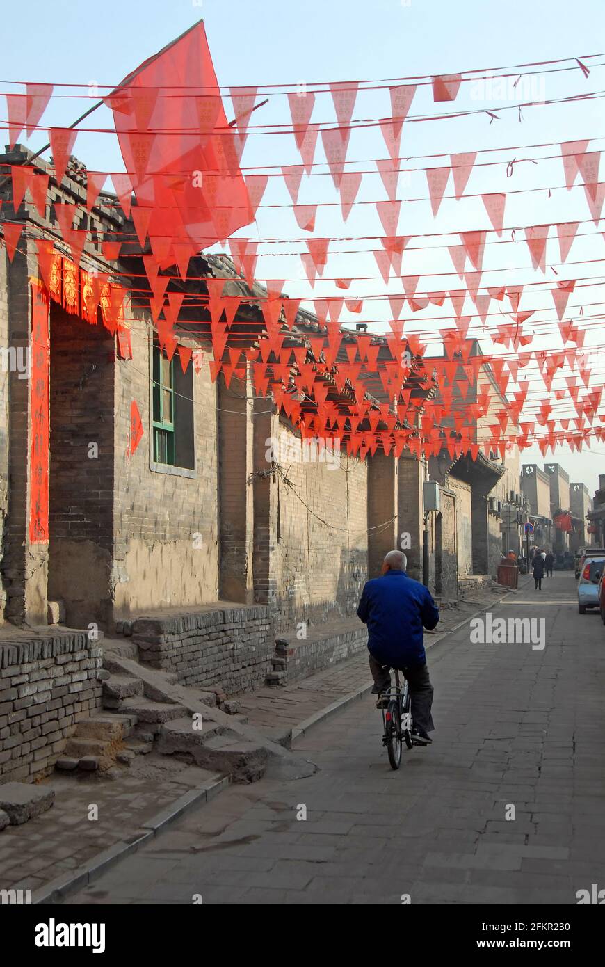 Un arrière-chemin à Pingyao, province du Shanxi, Chine avec des drapeaux rouges survolant la route et un vieux vélo. Banque D'Images