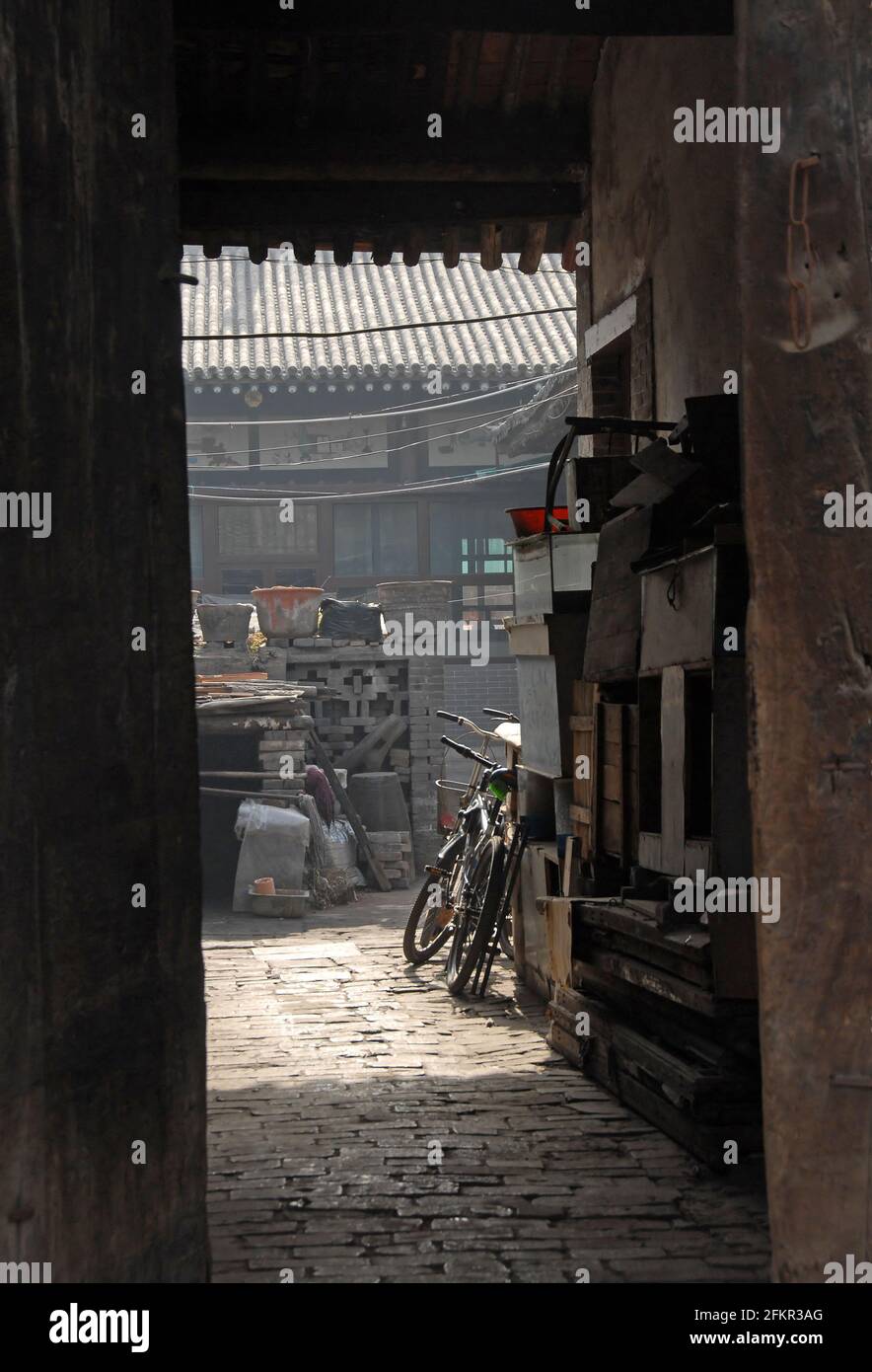 Pingyao dans la province du Shanxi, Chine : vue par une porte dans une allée et une cour avec des vélos Banque D'Images