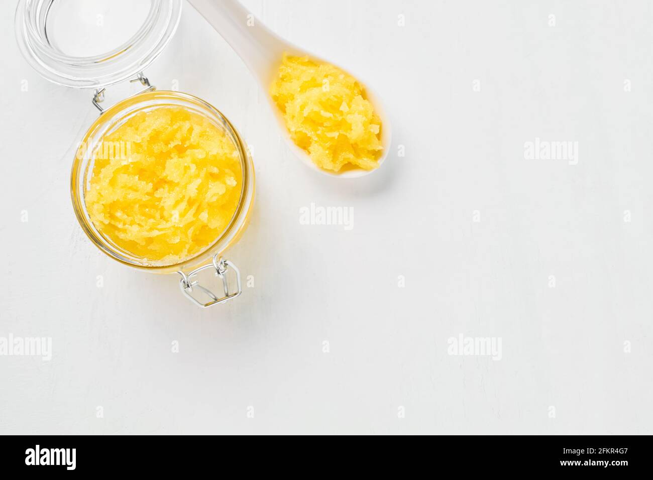 Gommage du corps jaune fait maison dans un pot en verre sur fond blanc. Concept SPA. Mise au point sélective, vue de dessus, espace de copie pour le texte. Banque D'Images