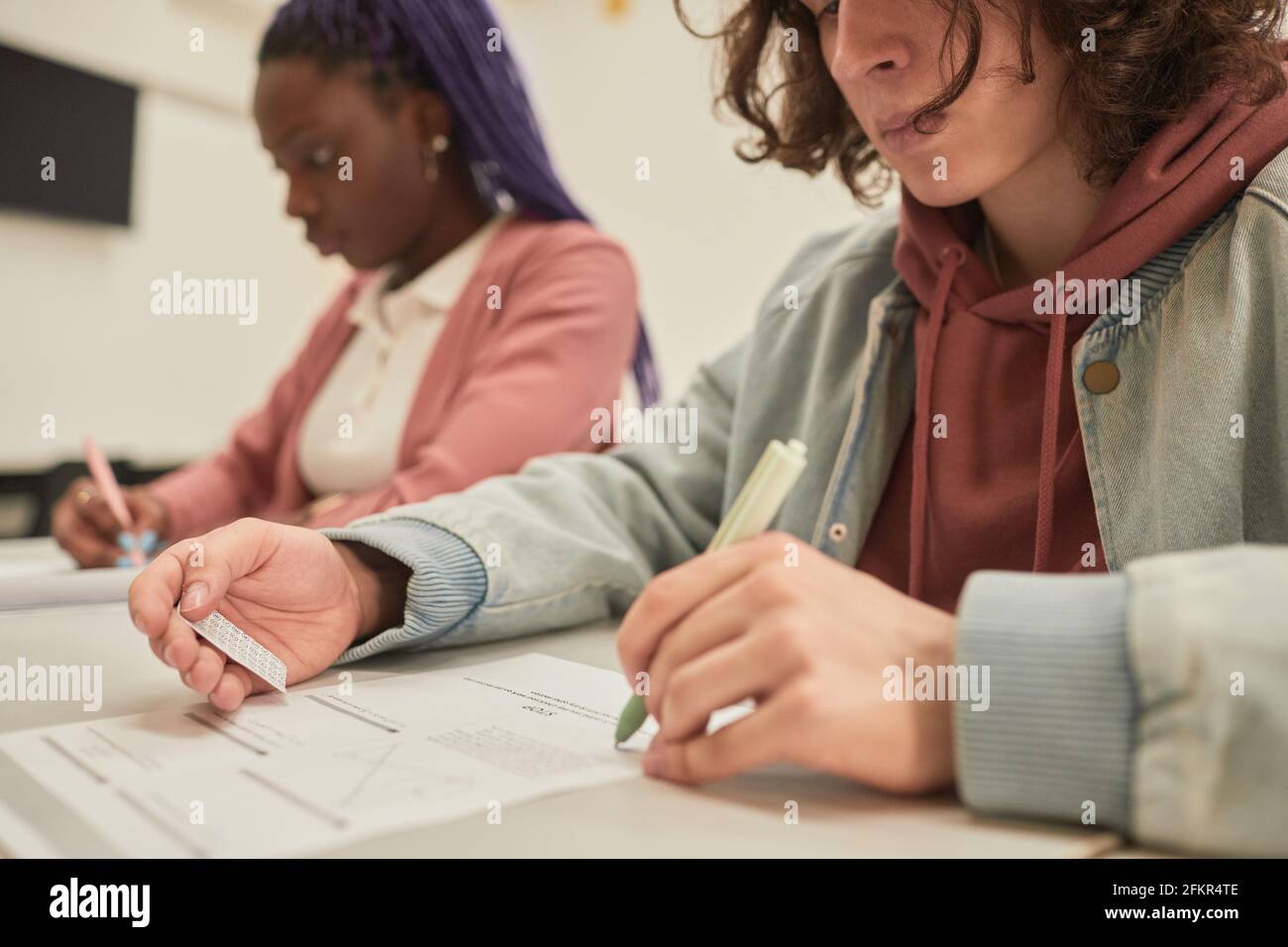 Portrait rogné d'un étudiant qui lit une note de triche tout en prenant l'examen à l'école, espace de copie Banque D'Images