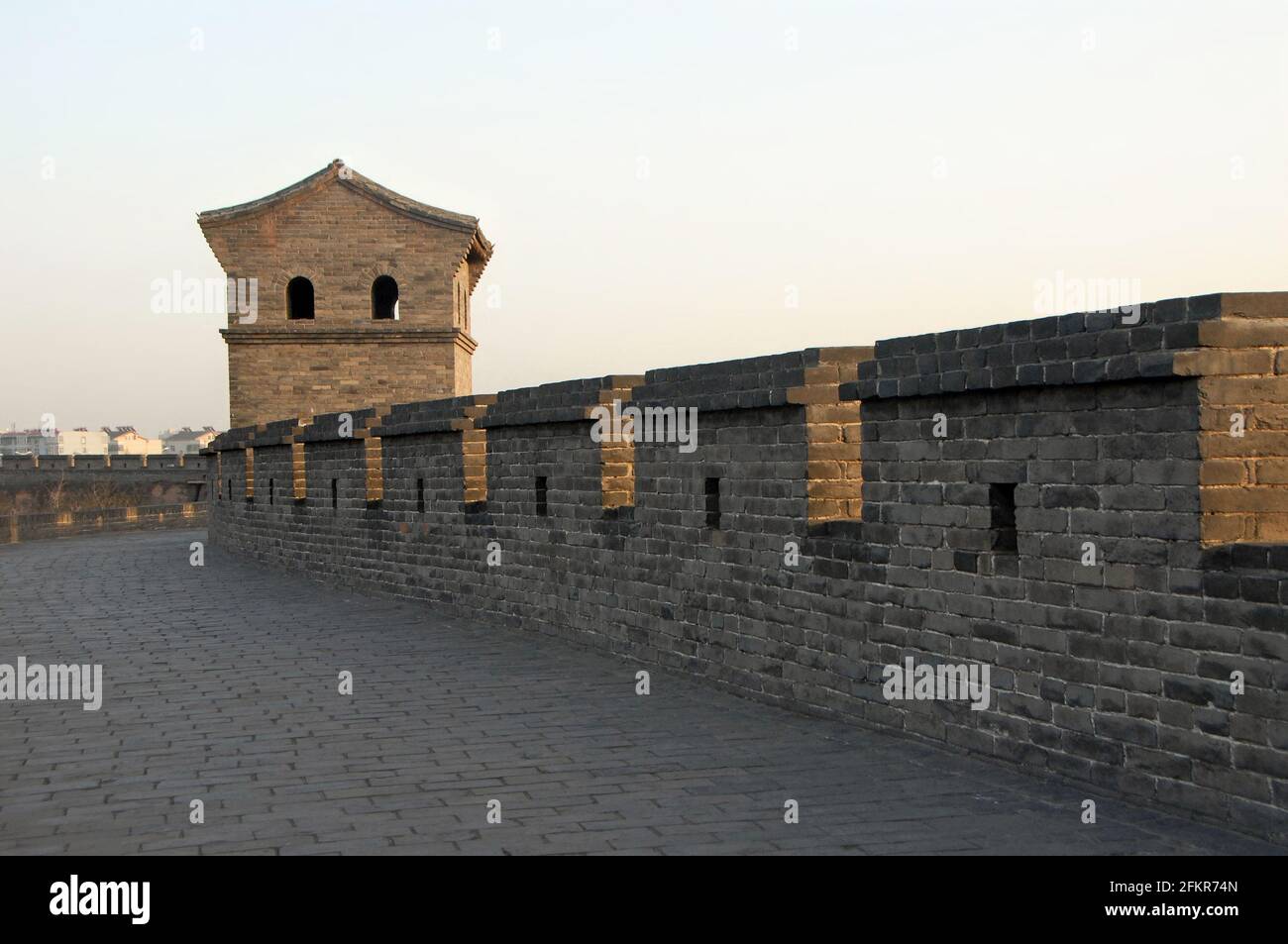 Pingyao dans la province du Shanxi, Chine. Mur de la ville de Pingyao avec une tour de guet vue depuis les remparts au soleil du soir. Banque D'Images