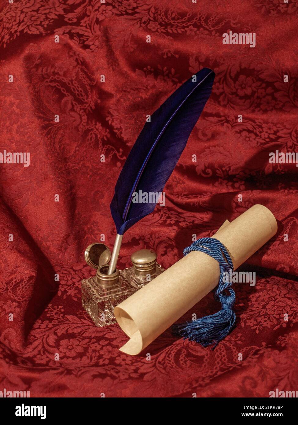bleu quill, verre inkwell et parchemin sur un tissu damassé rouge, dans une photo qui vous ramène dans le temps Banque D'Images