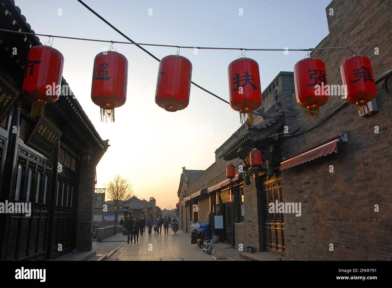 Pingyao dans la province du Shanxi, Chine: Scène de rue dans la ville antique de Pingyao au coucher du soleil avec des lanternes rouges près de la porte sud. Banque D'Images