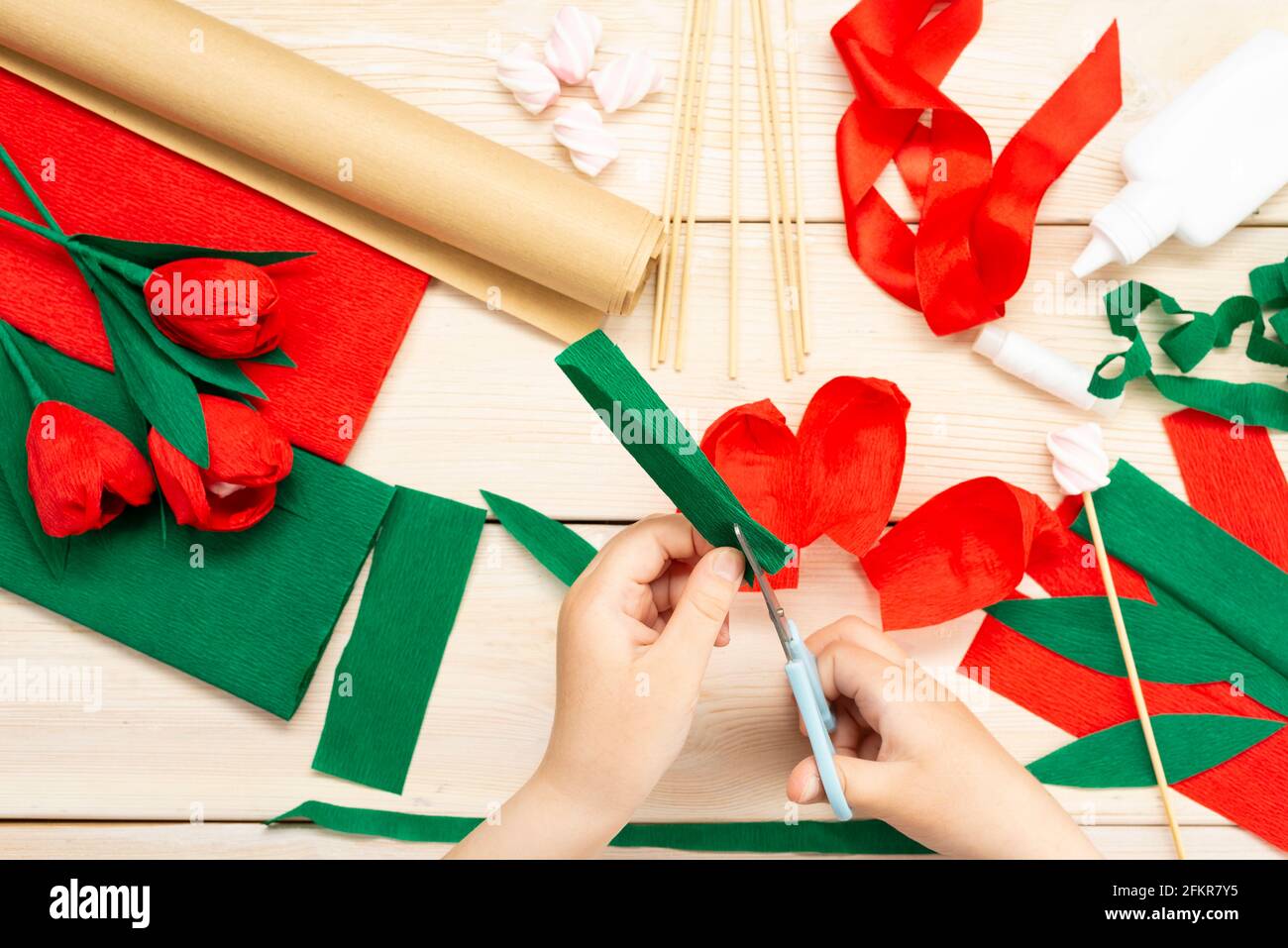 Comment faire une fleur de tulipe à partir de papier et de guimauves à la maison. Guimauve à l'intérieur d'un bourgeon rouge de tulipe. Les mains font une tulipe rouge. Instructions pas à pas Banque D'Images