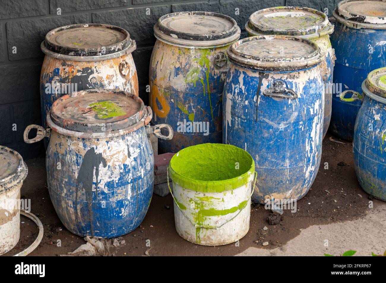 Déchets industriels, fûts de peinture en plastique. Vue en grand angle des liquides dans les conteneurs contre le mur. Banque D'Images