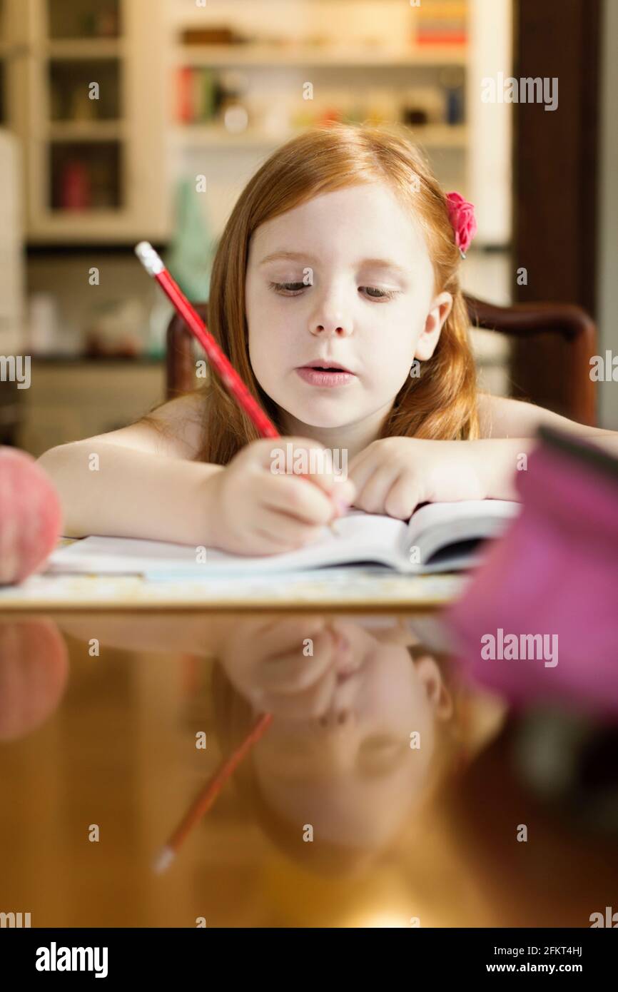 Girl doing homework at école table de salle à manger Banque D'Images