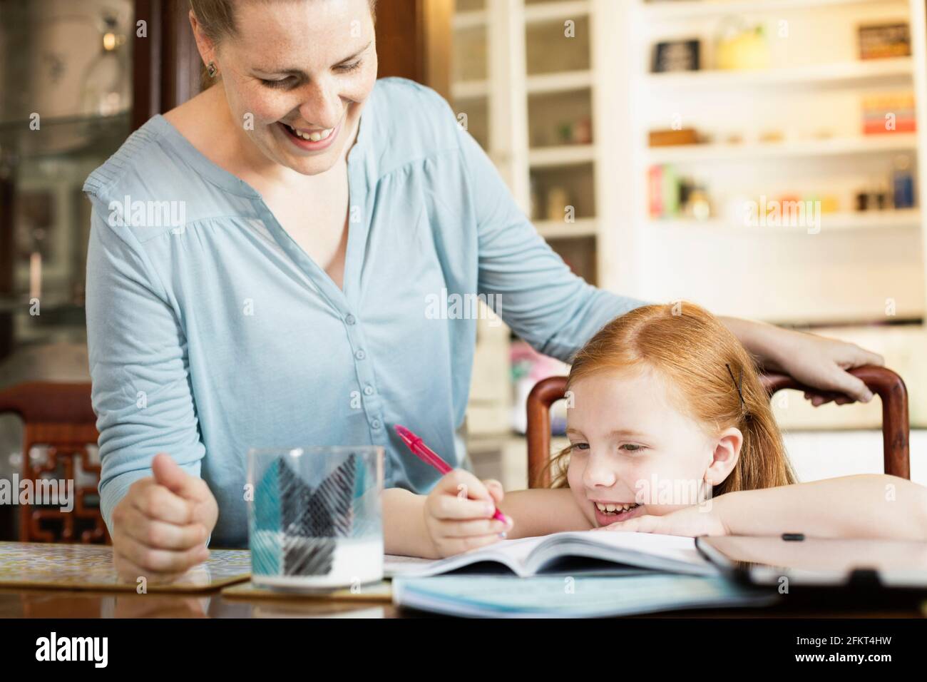 Mid adult mother helping daughter avec l'école devoirs à la table de salle à manger Banque D'Images