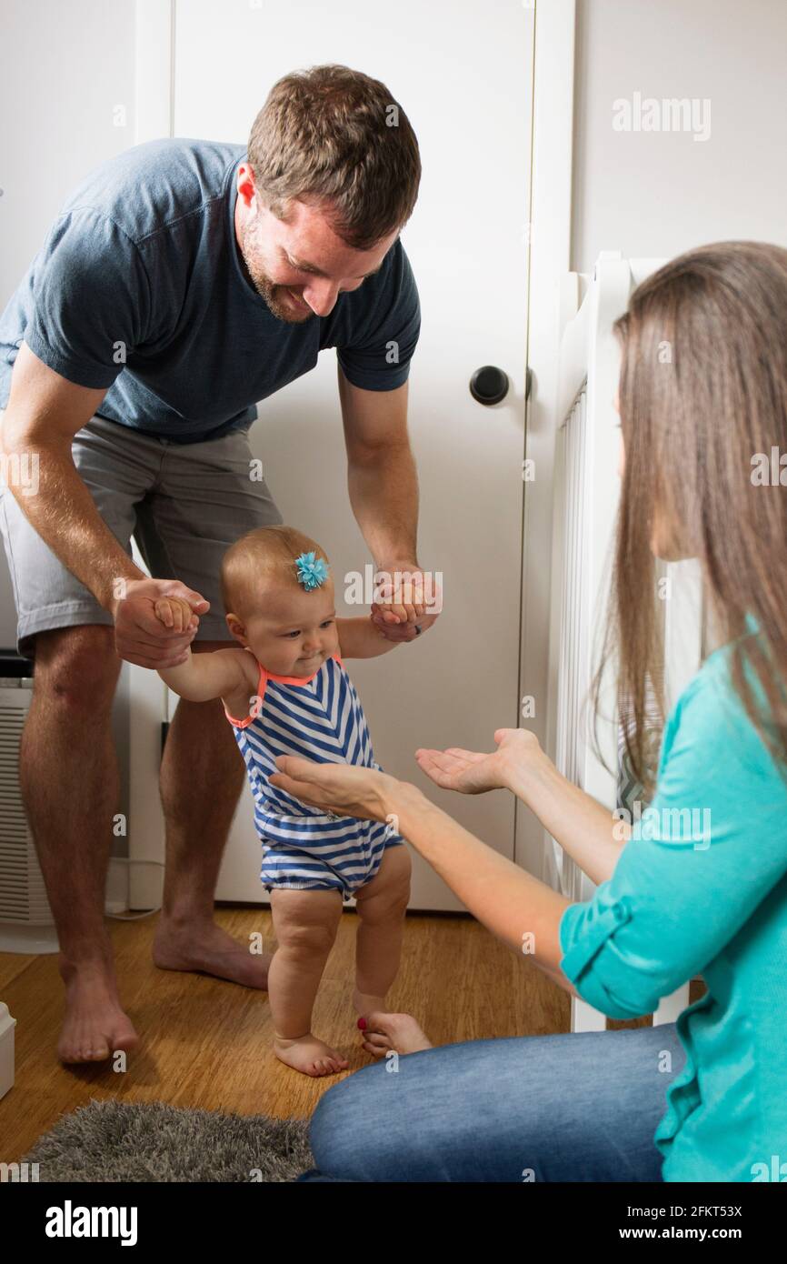 Mid adult man holding baby fille instable alors que les mains d'une façon incertaine dans les jardins Banque D'Images