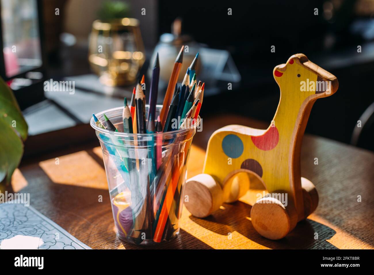 Girafe en bois, crayons de couleur et livre de coloriage sur une table en bois. Banque D'Images