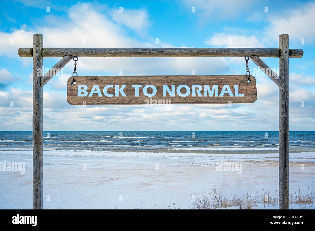 Panneau en bois avec texte de retour à la normale contre le ciel bleu, la mer et la plage avec le sable blanc. Concept de voyage et de vacances. Banque D'Images