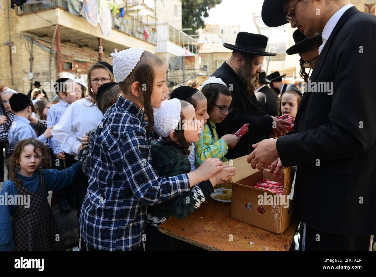 Des enfants orthodoxes juifs attendent en file pour de la nourriture et des bonbons servis par un homme juif juste pendant les préparatifs de la Pâque à MEA She'arim Jérusalem. Banque D'Images