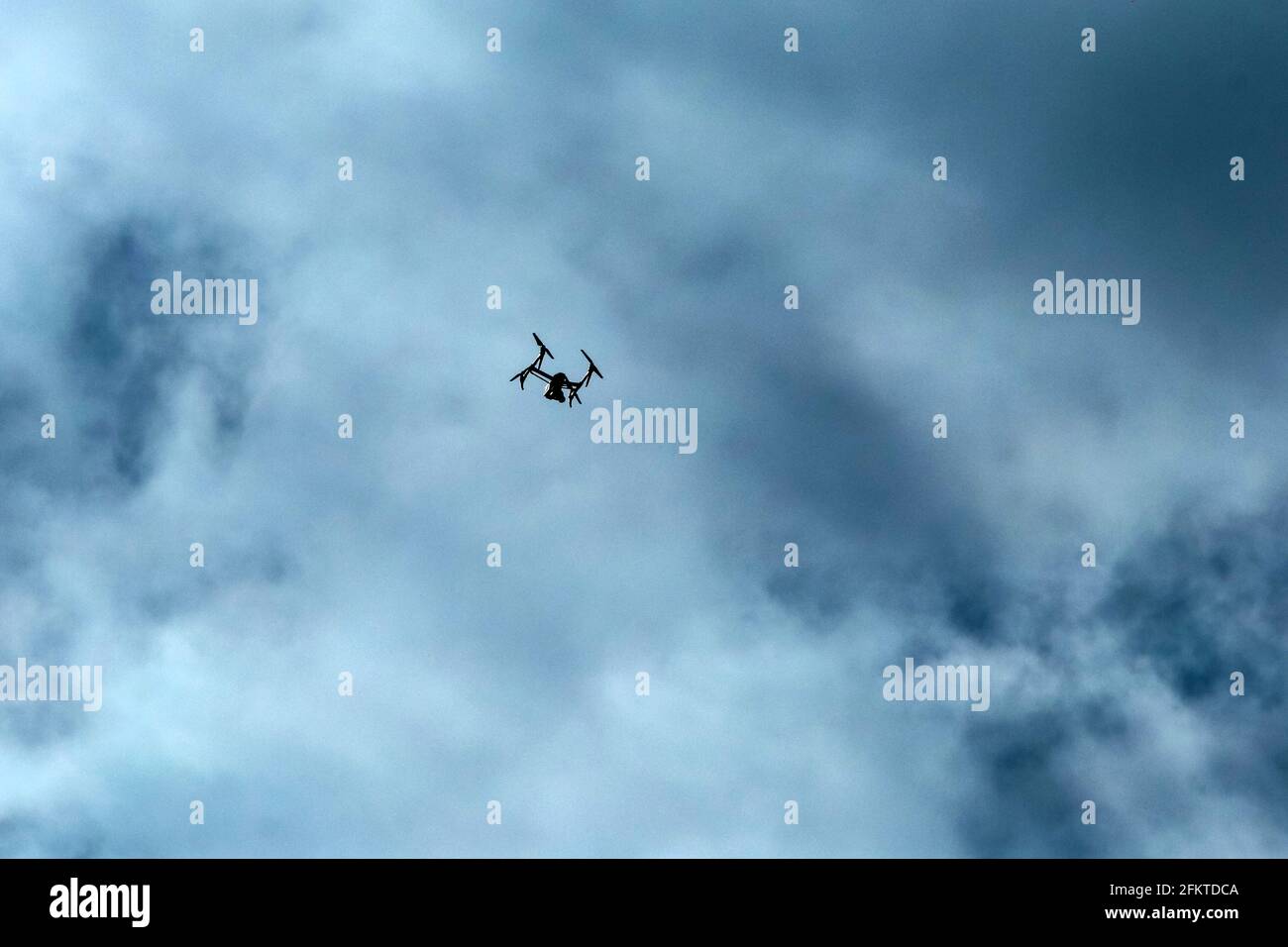Le petit drone volant haut photographié contre le ciel nuageux. Seule la silhouette est visible. Banque D'Images
