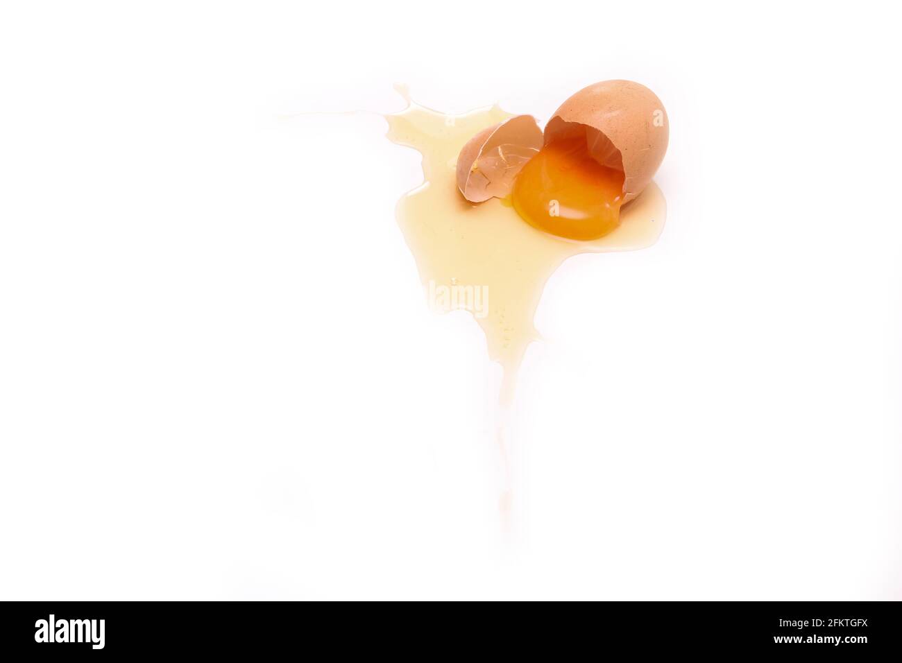 L'œuf biologique déchu est brisé avec la coquille d'œuf écrasée et le jaune d'œuf et le blanc s'écoulant de celui-ci. Banque D'Images