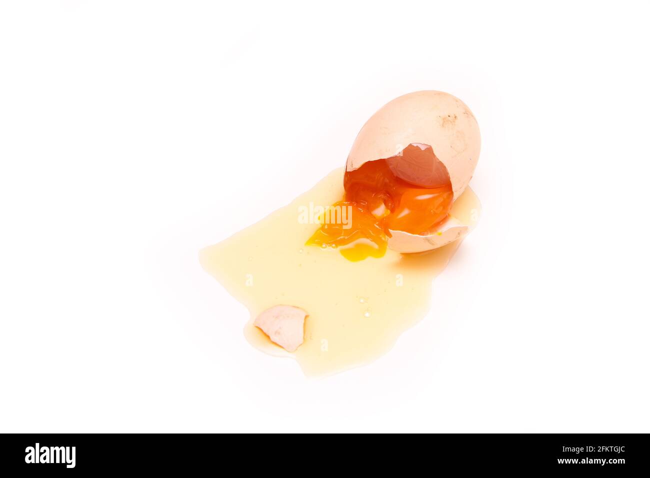L'œuf biologique déchu est brisé avec la coquille d'œuf écrasée et le blanc s'en écoule. Le jaune est déjà dur, presque pourri. Banque D'Images