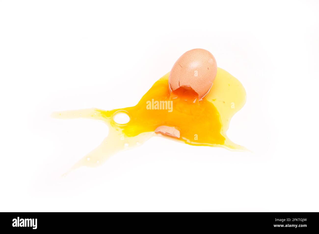 L'œuf biologique déchu est brisé avec la coquille d'œuf écrasée et le jaune d'œuf et le blanc s'écoulant de celui-ci. Banque D'Images