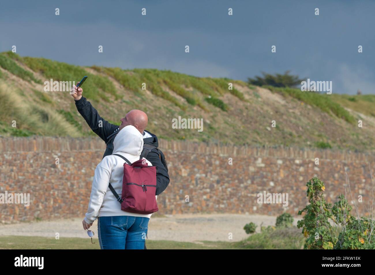 Deux vacanciers utilisant un smartphone pour prendre une photo de selfie en vacances à Newquay, en Cornouailles. Banque D'Images