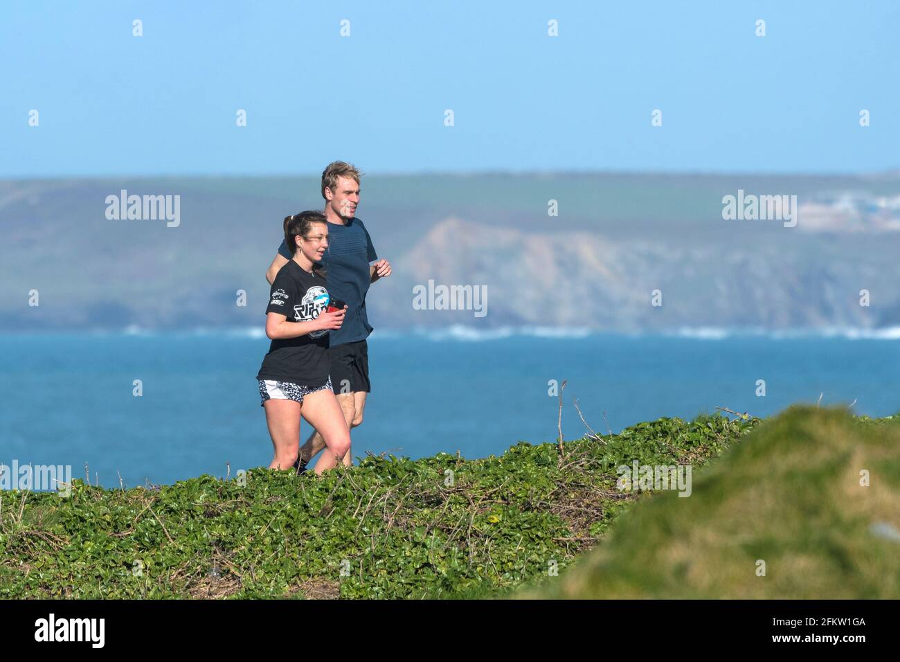 Un coureur mâle et un coureur femelle sur le sentier côtier de Newquay, en Cornouailles. Banque D'Images
