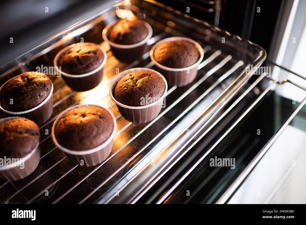 Ouvrez le four maison avec des muffins au chocolat sous forme de bakeing  sur le plateau à la maison. Faire des petits gâteaux frais dans la  cuisinière gros plan Photo Stock -