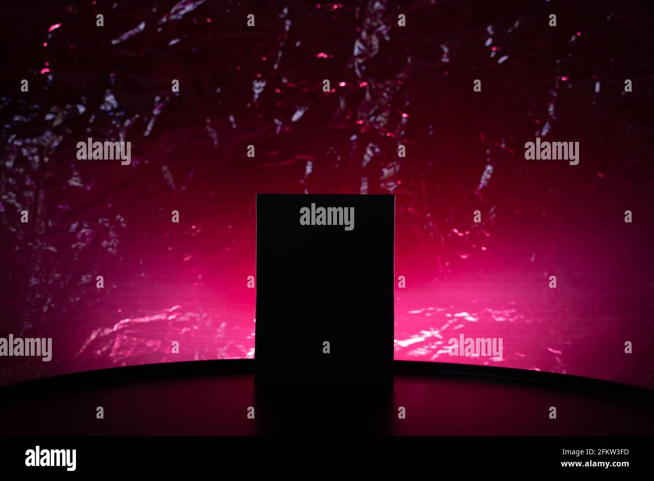 Podium noir avec éclairage rose chaud et arrière-plan texturé Banque D'Images