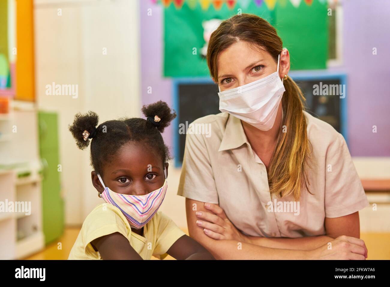 Fille africaine et éducatrice avec masque facial à la maternelle parce que De Covid-19 Banque D'Images