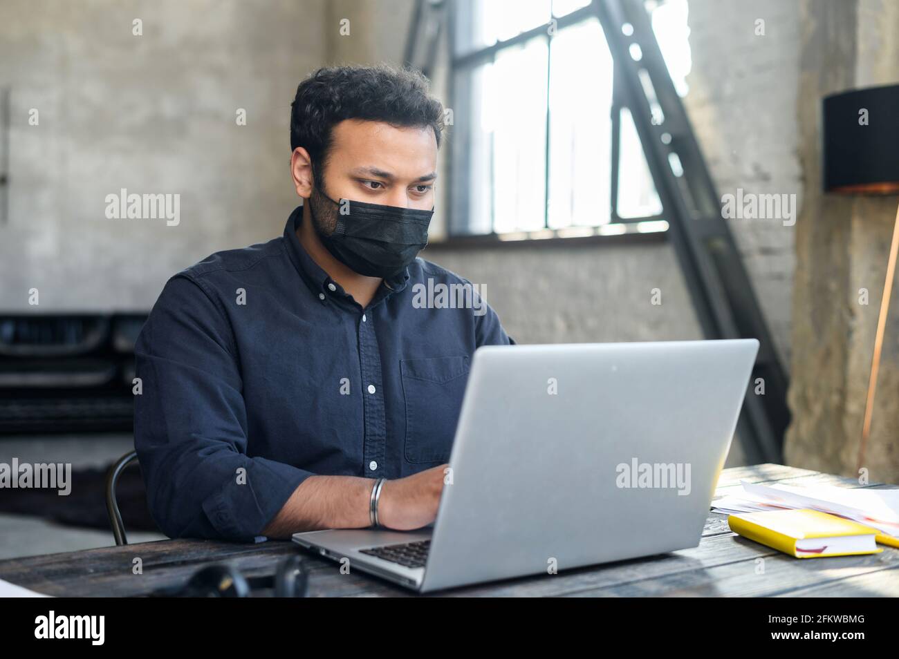 Employé de race mixte hindou portant un masque de protection travaillant dans l'espace de bureau. Mesure visant à protéger le personnel de bureau contre les maladies virales pendant la période pandémique Banque D'Images