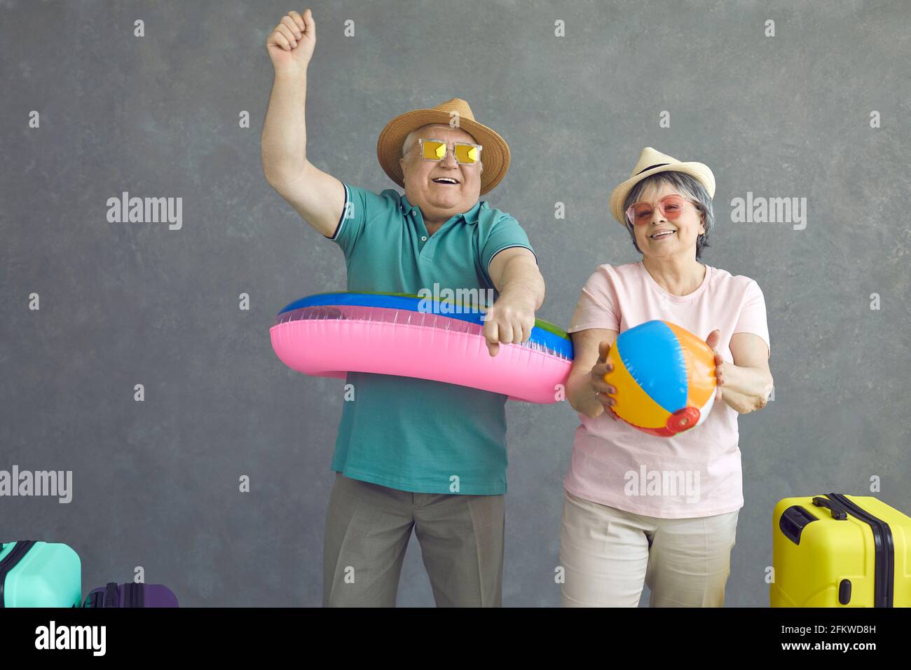 Studio portrait de couple senior heureux dansant et s'amusant avec jouets gonflables de plage Banque D'Images