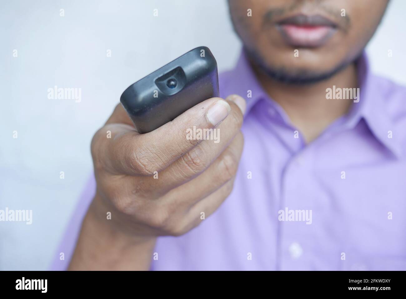 gros plan sur un homme tenant la télécommande du téléviseur. Banque D'Images