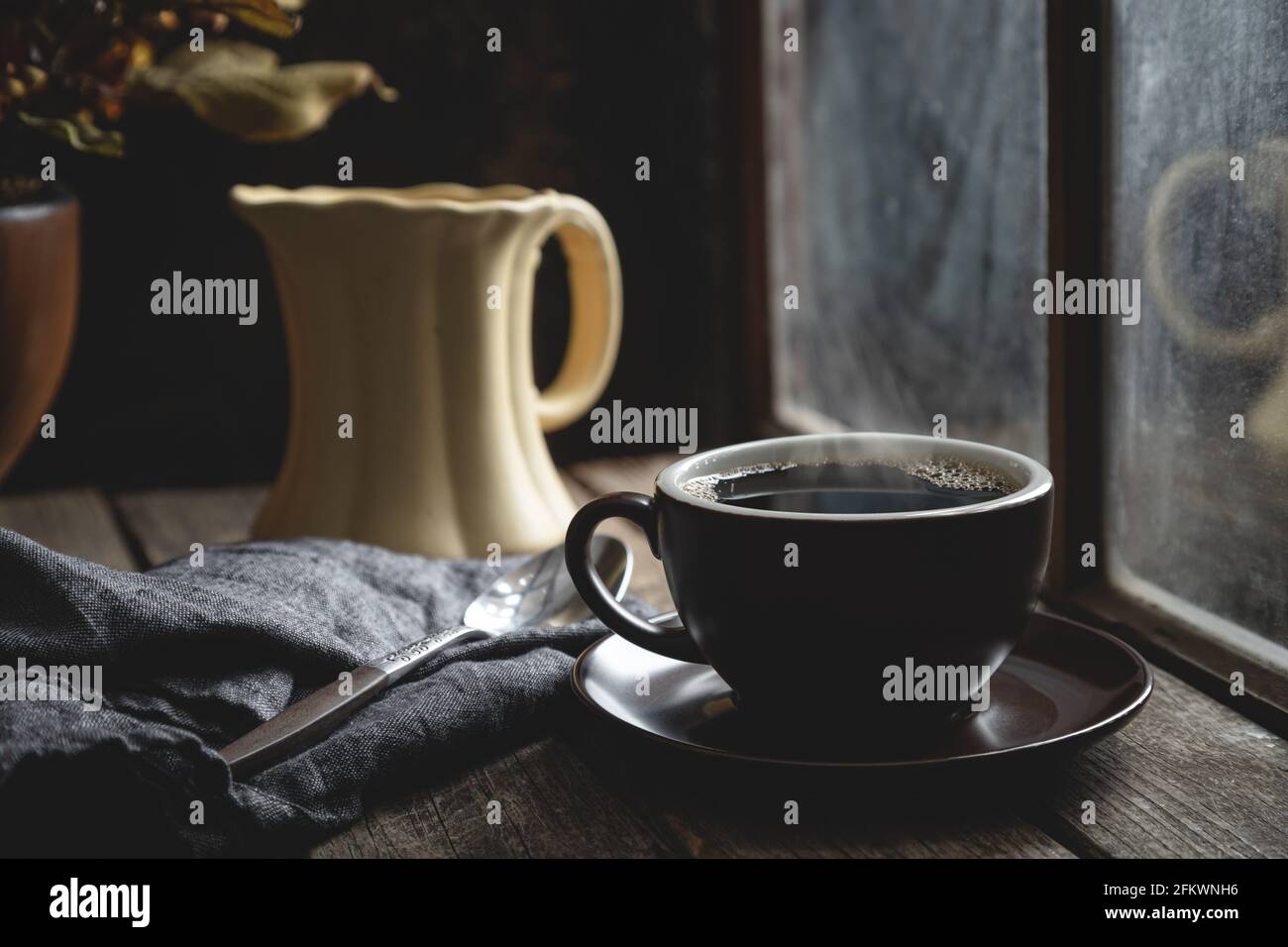 Tasse de café chaud sur une table rustique en bois une fenêtre Banque D'Images