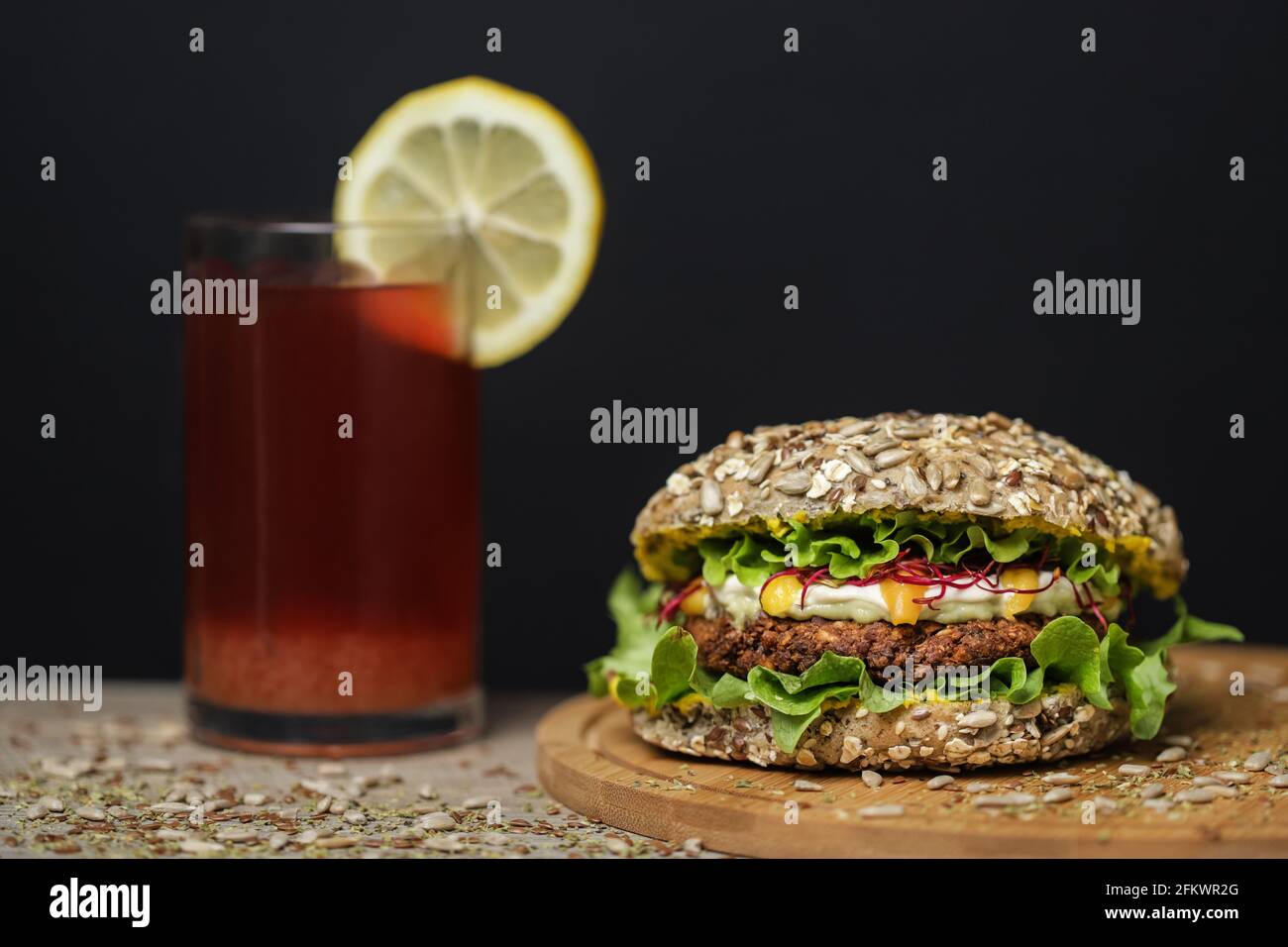 jus à côté d'un hamburger végétarien sain sur une assiette en bois Banque D'Images