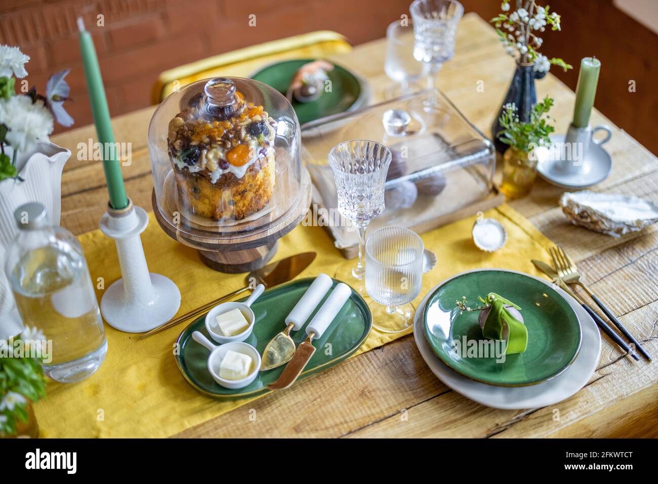 Concept joyeuses Pâques. Beaux réglages de table de printemps, assiette  verte avec oeuf, panettone sur le support à gâteau, bougies vertes, et  branche de fleurs de pomme dans le vase. Nappe de