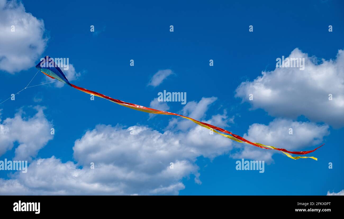 Cerf-volant traditionnel avec queue colorée sur fond ciel bleu nuageux, jour ensoleillé. Activités de loisirs pour enfants et adultes, concept de bonheur de liberté. Banque D'Images