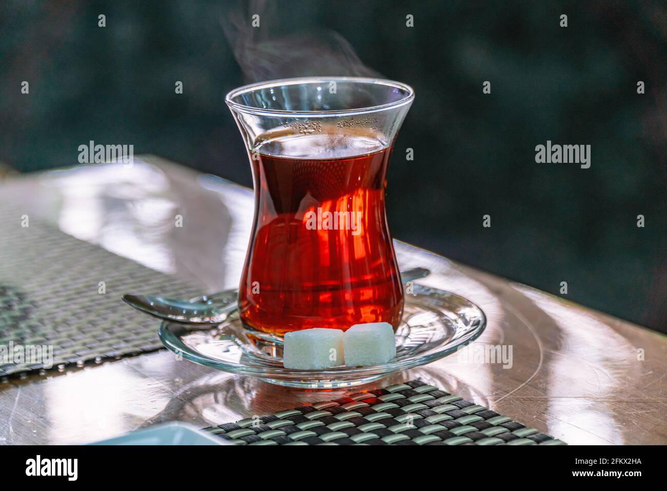 Gros plan d'une tasse de verre turc traditionnel, bardak, de thé noir turc avec du sucre et une cuillère Banque D'Images