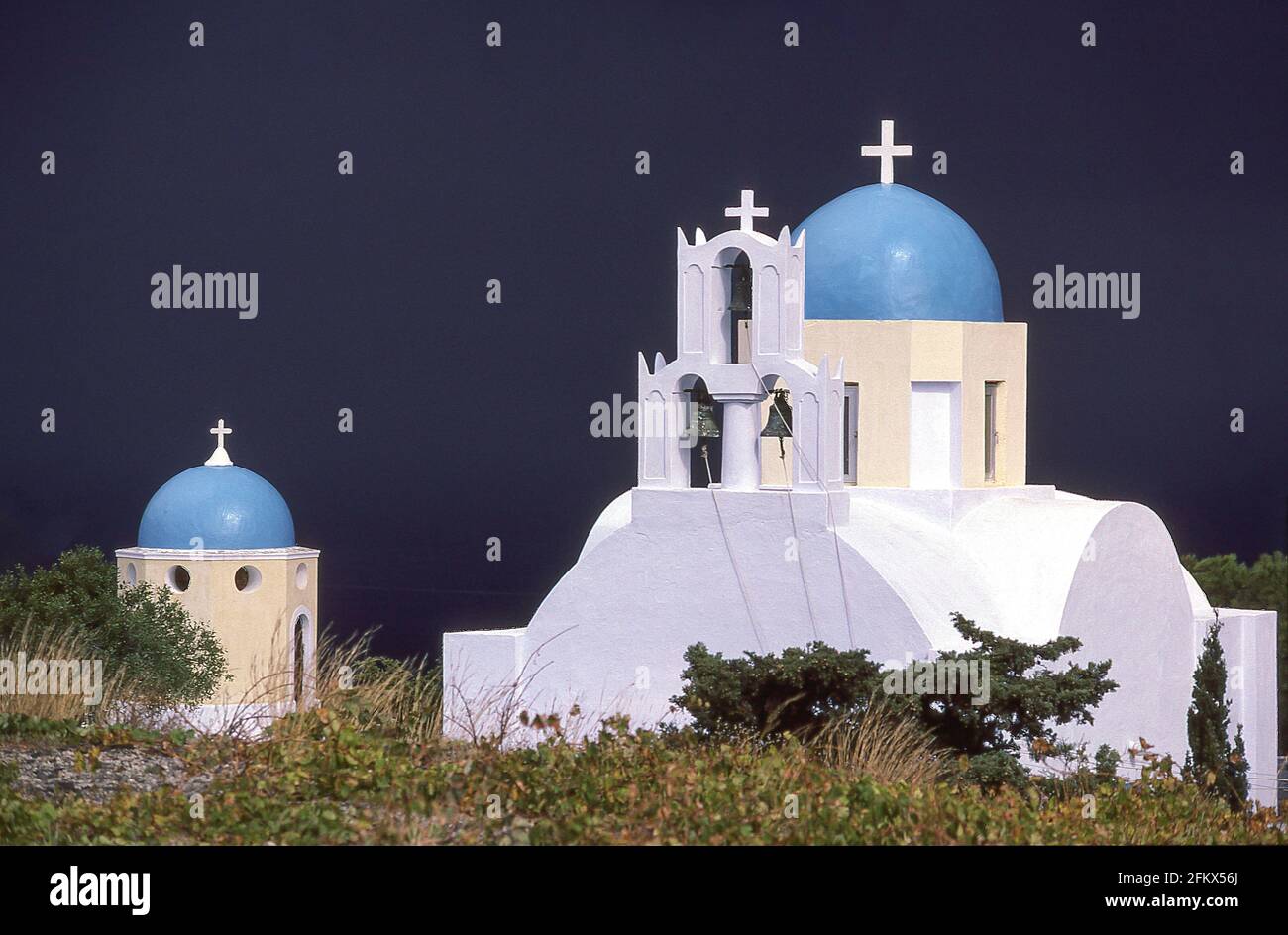 Église éclairée par le soleil avec des nuages sombres de tempête derrière, Fira, Santorin, les Cyclades, sud de la mer Égée, Grèce Banque D'Images
