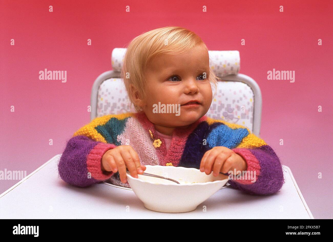 Jeune fille mangeant repas sur chaise haute, Winkfield, Berkshire, Angleterre, Royaume-Uni Banque D'Images