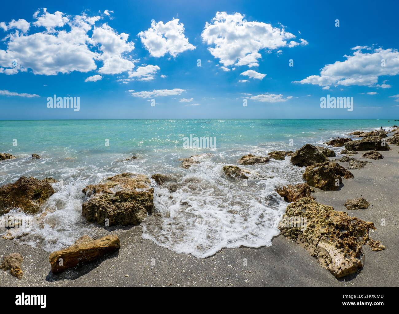 Petites vagues brisant des rochers sur la rive du GILF du Mexique à la plage de Caspersen avec ciel bleu et Nuages blancs à Venise Floride États-Unis Banque D'Images