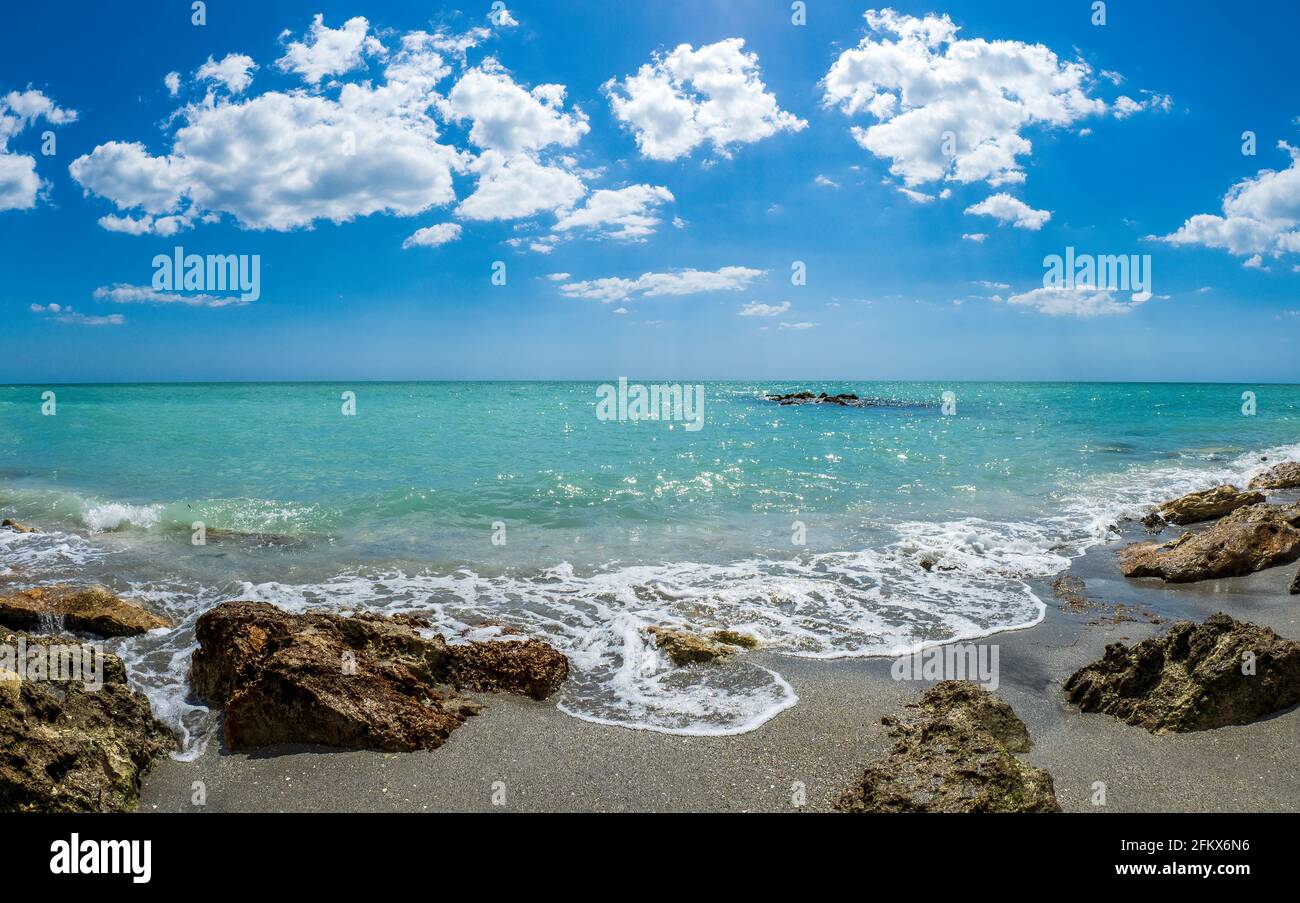 Petites vagues brisant des rochers sur la rive du GILF du Mexique à la plage de Caspersen avec ciel bleu et Nuages blancs à Venise Floride États-Unis Banque D'Images