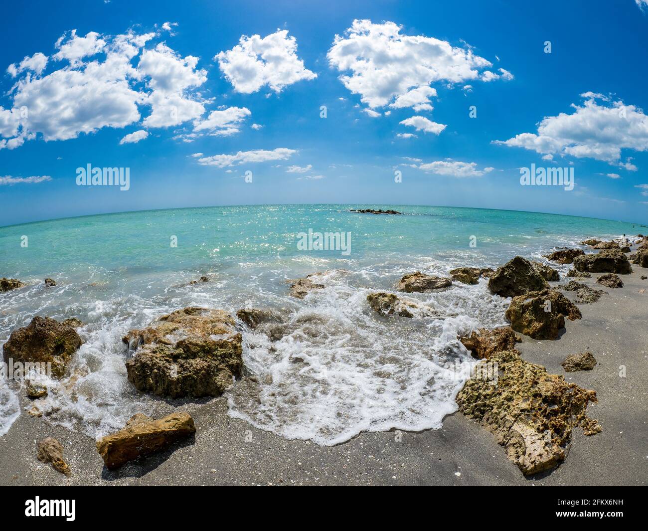 Petites vagues brisant des rochers sur la rive du GILF du Mexique à la plage de Caspersen avec ciel bleu et Nuages blancs à Venise Floride États-Unis Banque D'Images