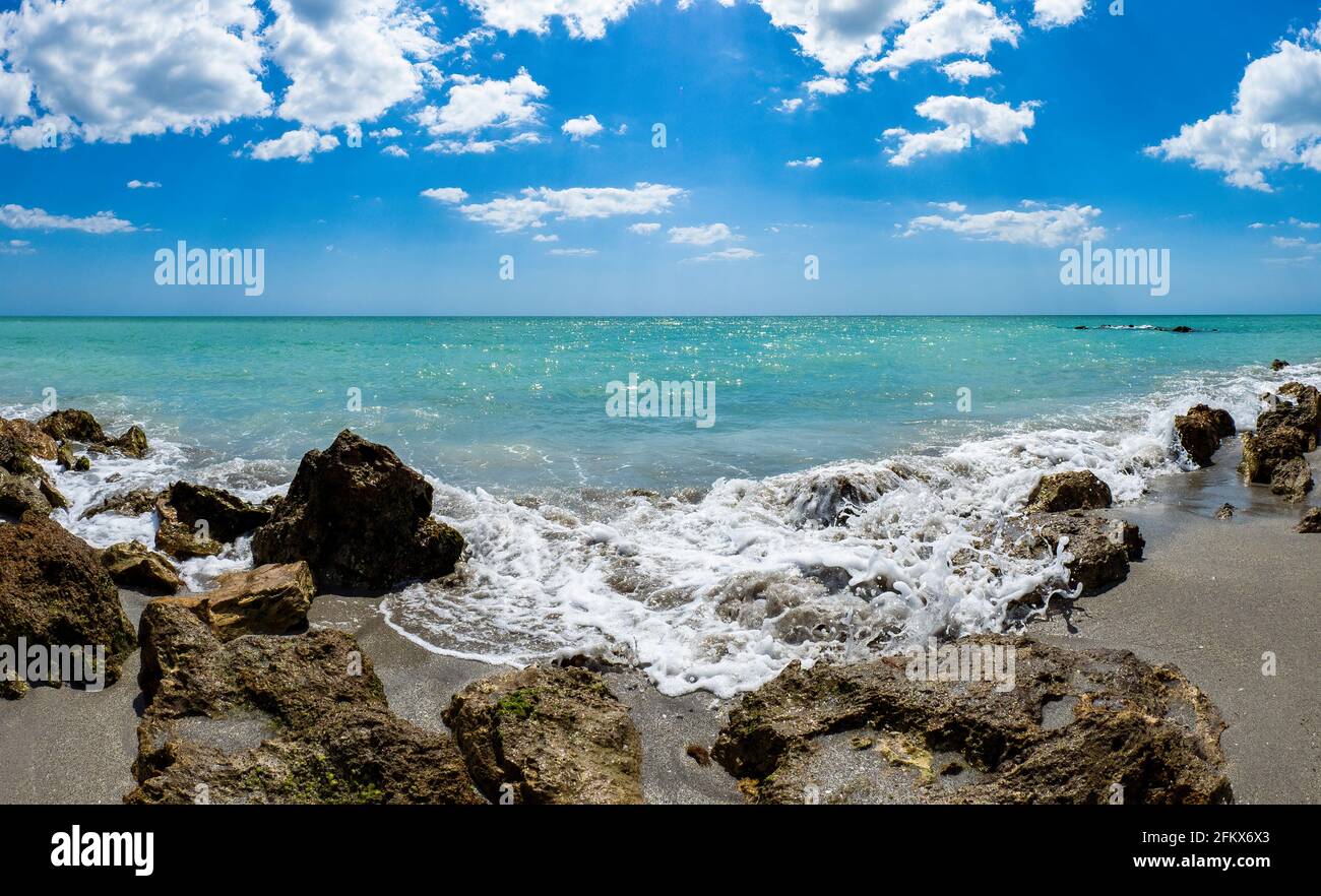 Petites vagues brisant des rochers sur la rive du GILF du Mexique à la plage de Caspersen avec ciel bleu et Nuages blancs à Venise Floride États-Unis Banque D'Images