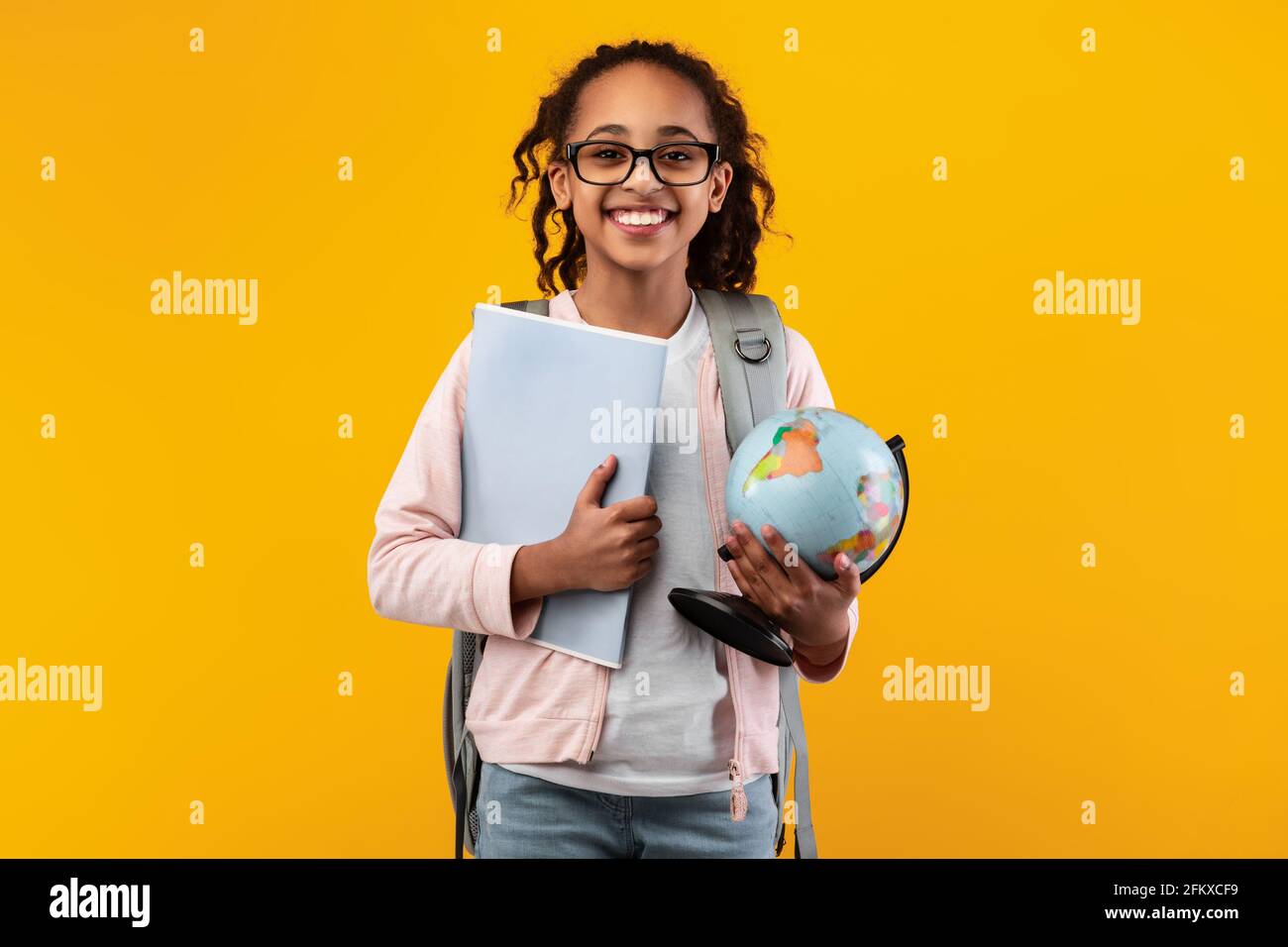 Jeune fille noire joyeuse tenant le globe terrestre et le carnet Banque D'Images