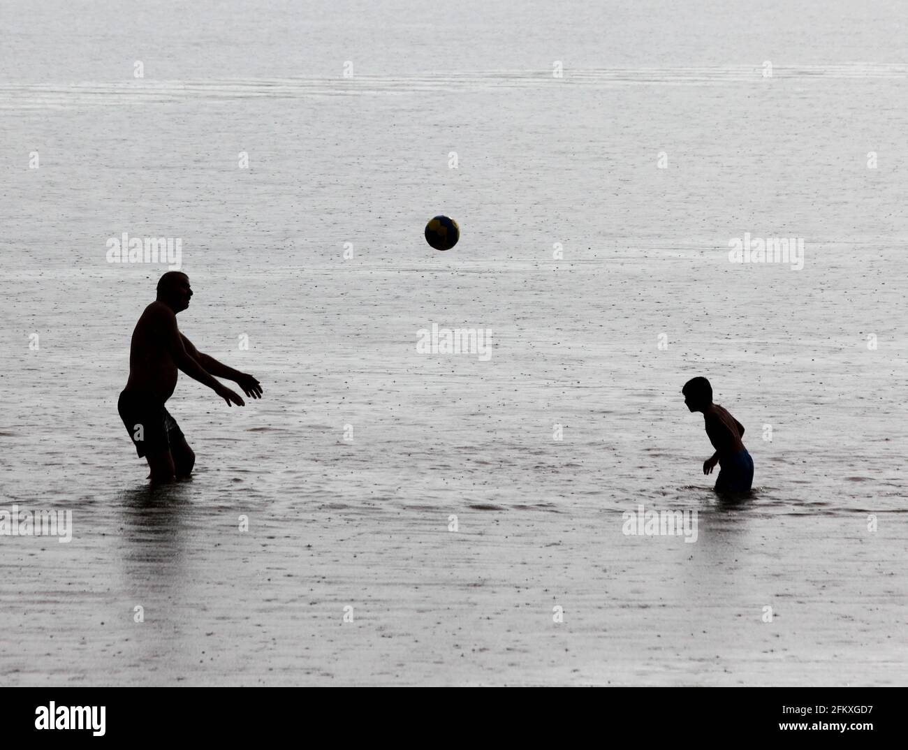 Certains qui se jettent une balle dans un lac quand il pleut, Motala, Suède. Banque D'Images