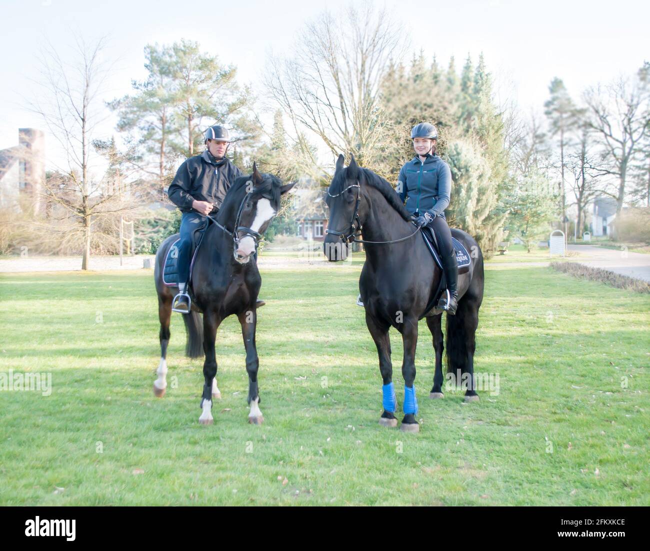 Krelingen, Allemagne, 1er avril 2019 : cavaliers sur de grands chevaux, un homme et une femme, sur une route dans un village en Allemagne. Vue arrière. Banque D'Images